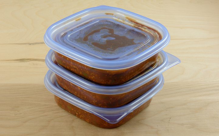 Batch of freshly made spaghetti sauce with ground turkey meat in plastic storage containers to prepare for freezer and meals in advance for work week