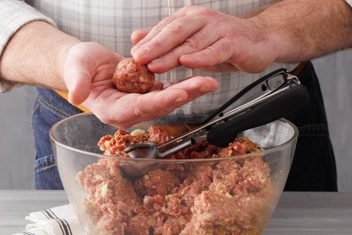 A person Hand Shaping Mixture Into Balls With Scoop In Bowl