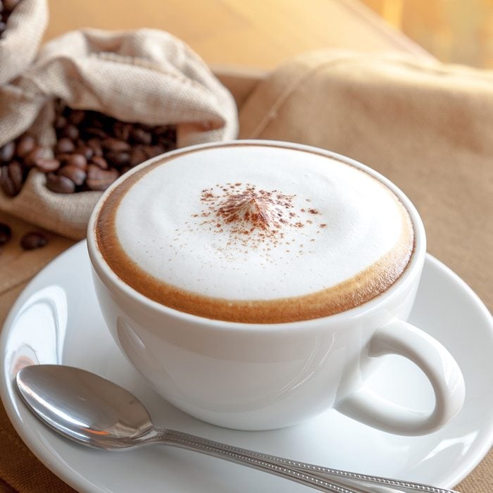 A cup of cappuccino with coffee beans