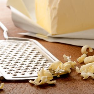 grated butter and grater on wooden board