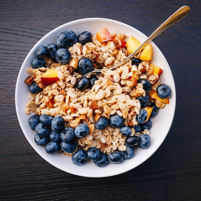 Healthy eating - bowl of organic porridge with blueberry and peach fruits for breakfast.