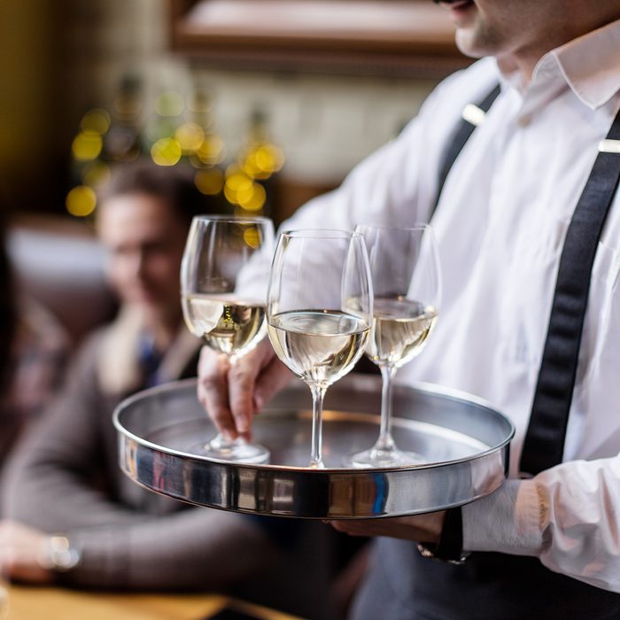 Waiter serving white wine in restaurant