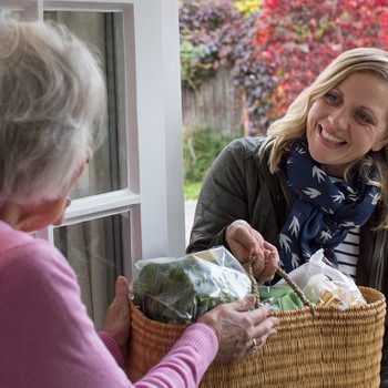 Female Neighbor Helping Senior Woman With Shopping