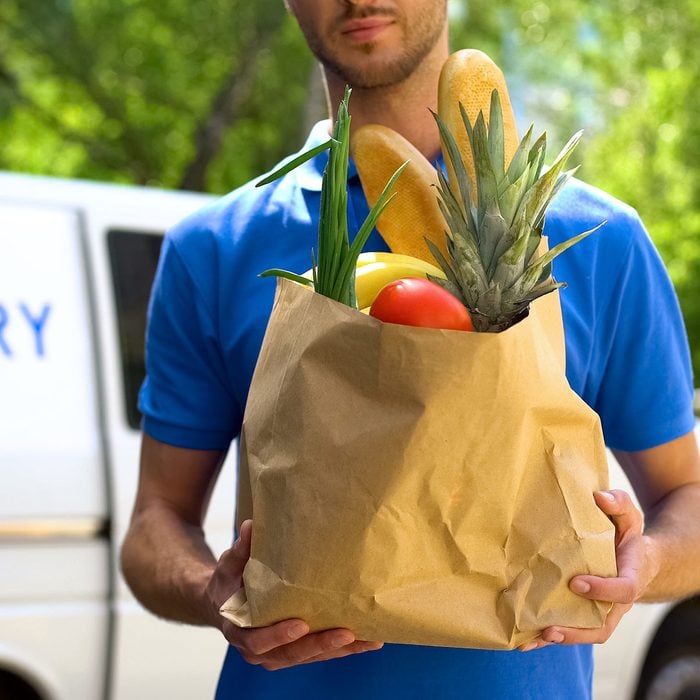 Food delivery service, male worker holding grocery bag, express food order
