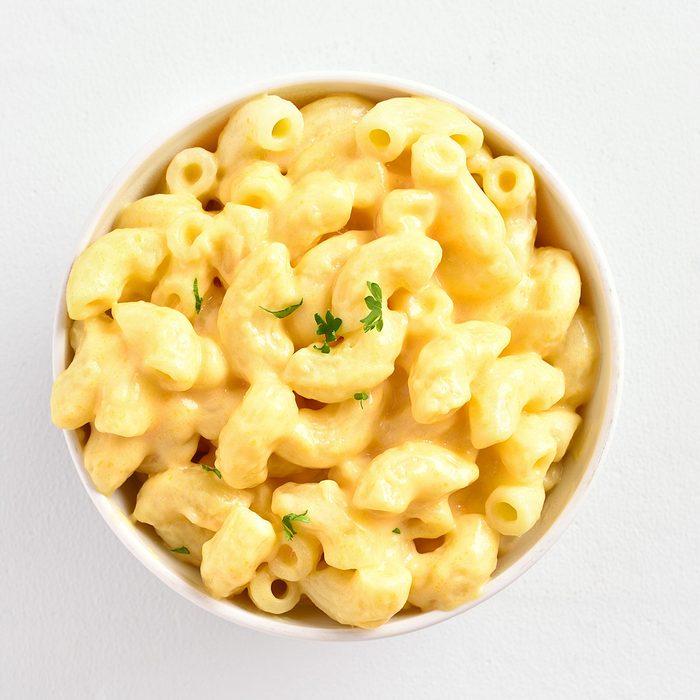 Macaroni and cheese in white bowl on white stone background with copy space. Top view, flat lay