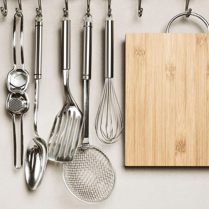 Kitchen detail, utensils for cooking hanging with hooks on the wall