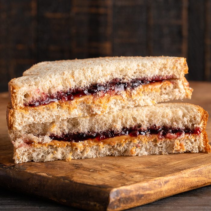 A Peanut Butter and Grape Jelly Sandwich on a Wooden Cutting Board