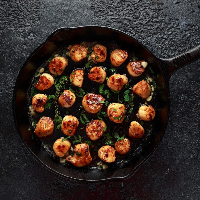 Scallops seared in garlic and parsley butter served in cast iron skillet.