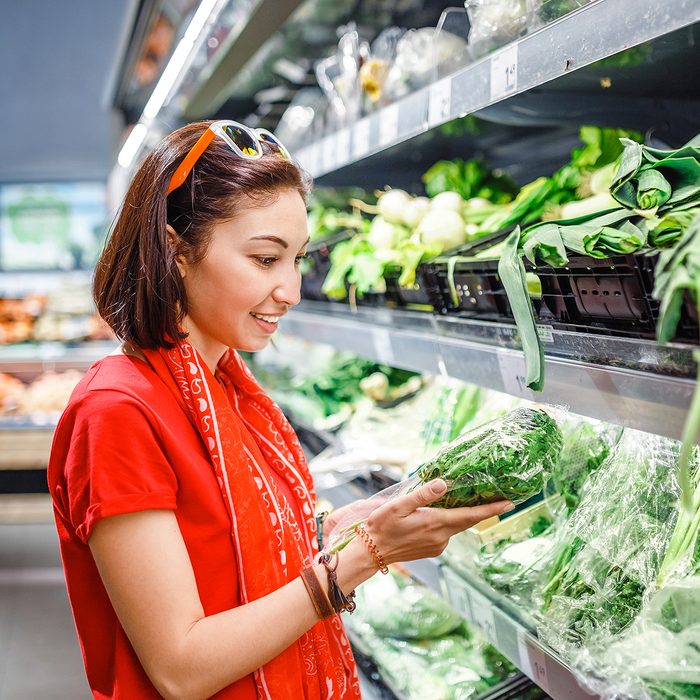 A woman in a supermarket chooses green vegetables, a concept of agriculture and a vegetarian diet
