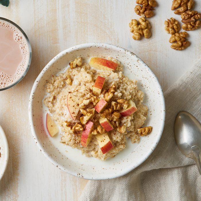 Oatmeal with apple, nuts, honey and cup of chocolate on white wooden light background. Top view. Healthy diet breakfast