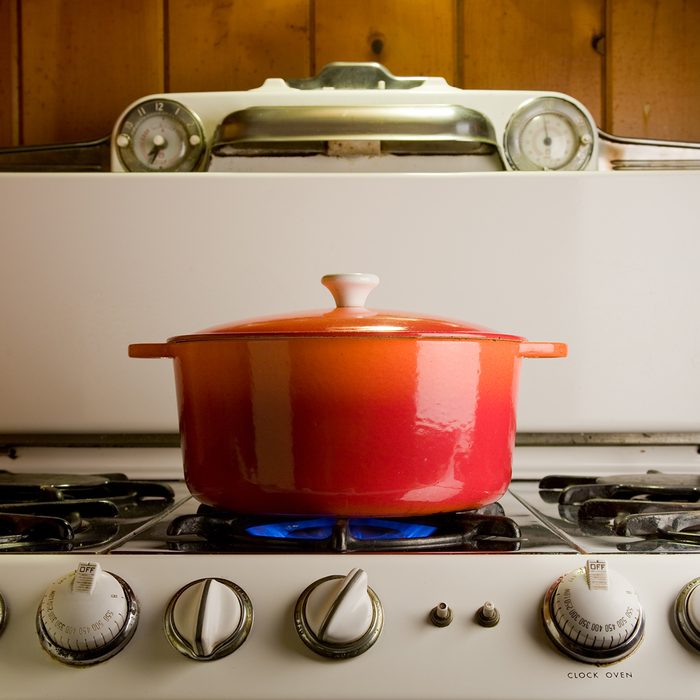 red cast iron pot cooking on antique stove