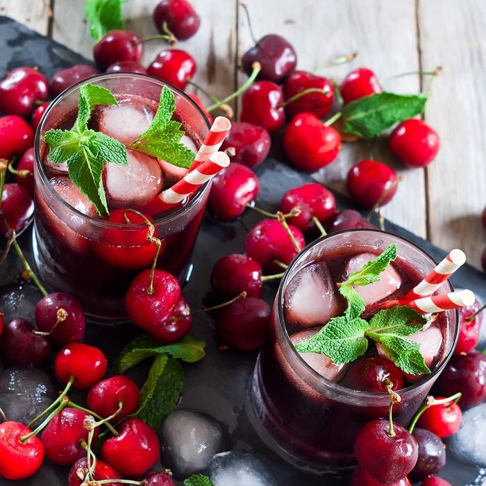 Cherry juice with ice cubes, mint leaves and ripe sweet cherry