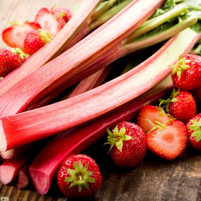 Fresh rhubarb and strawberries on a wooden underground