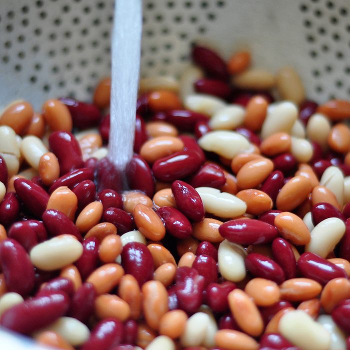 Three types of beans being rinsed in a colander.