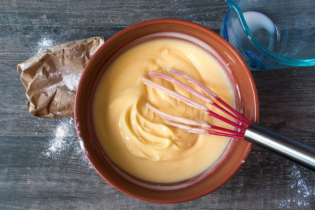 Mixing vanilla pudding with ingredients on rustic table Flat lay