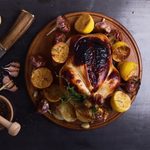 Grilled chicken with lemon, garlic and thyme on wooden board, top view