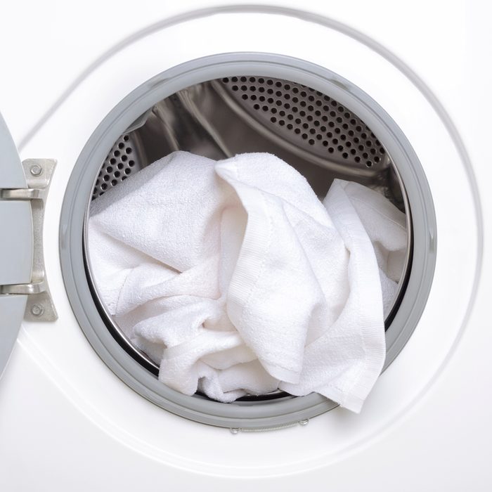 Housekeeper taking out clean clothes from washing machine,closeup