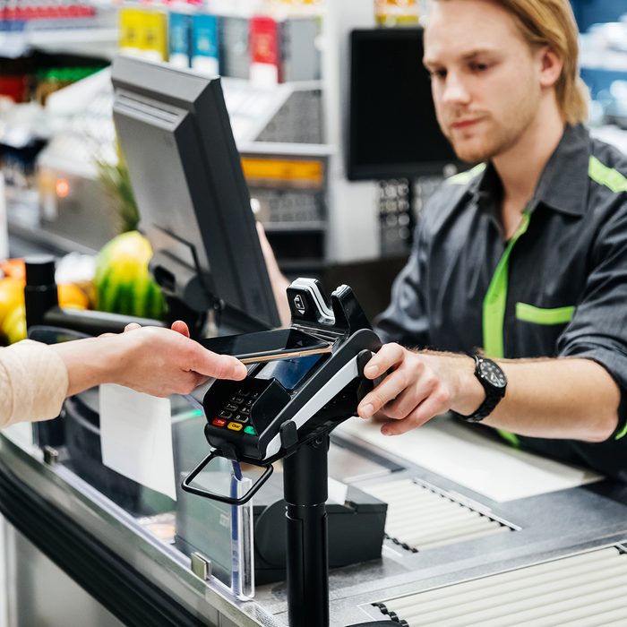 A woman paying for her groceries with her smartphone, using the contactless payment option.