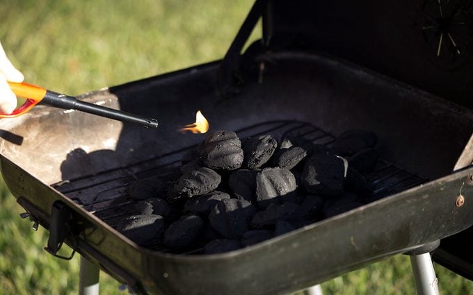 Person starting barbecue grill flame