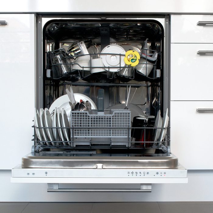 Open dishwasher with dirty dishes and surrounding cabinets