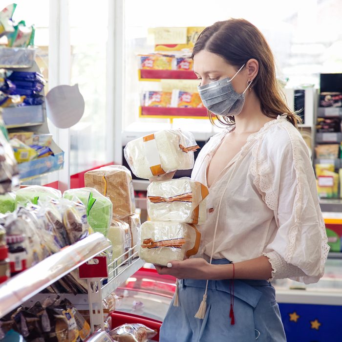 Woman wearing protective mask while grocery shopping in supermarket, Coronavirus contagion fears concept