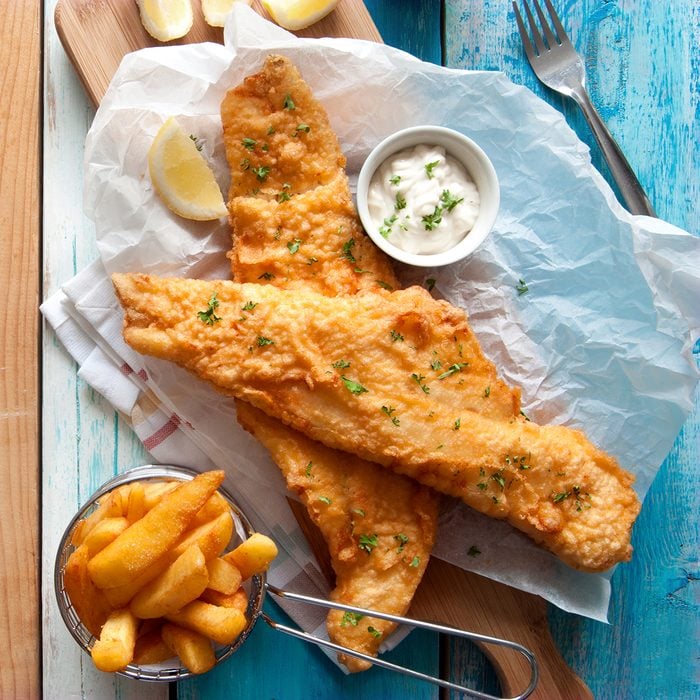 Traditional British fried fish in batter with chips in a basket