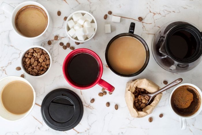 overhead view of Different types of coffee in cups on marble countertop
