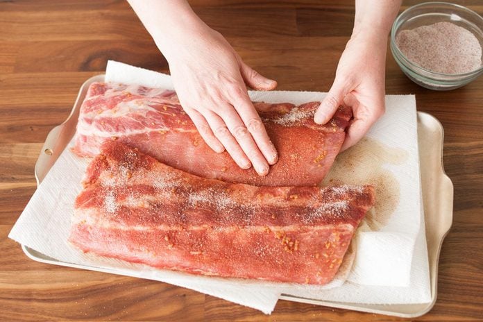 adding dry rub on ribs to prepare for grilling