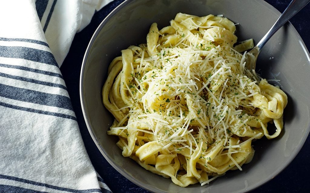 fresh, homemade egg noodles in a bowl topped with parmesan and butter