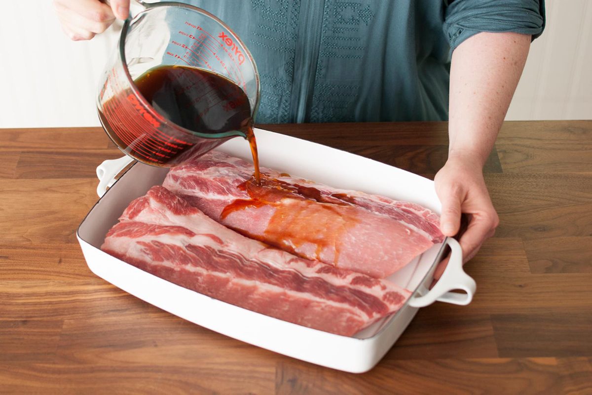 pouring marinade over ribs to prepare for grilling