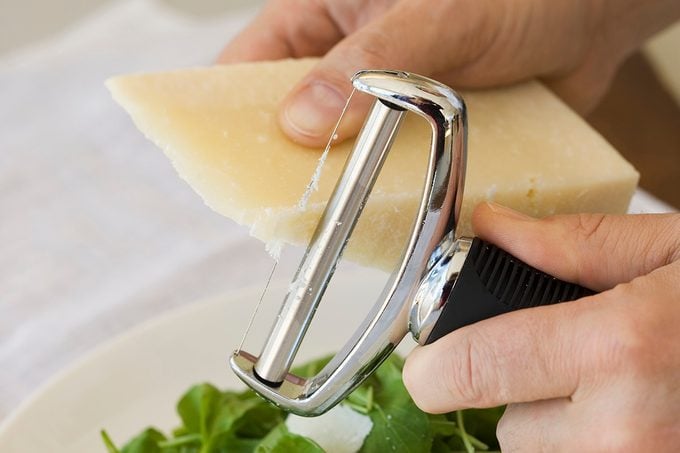 Man shaving Parmesan cheese onto salad
