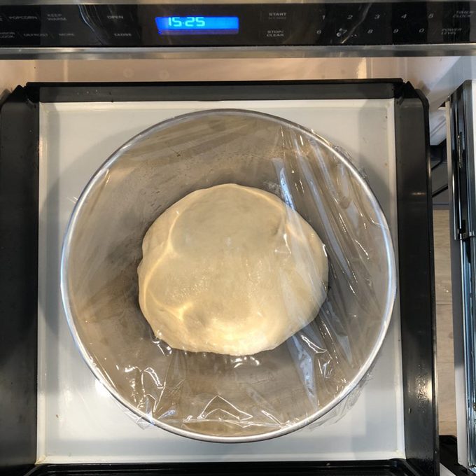 Dough rising in bowl covered with plastic wrap