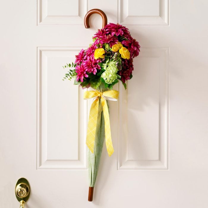 flowers in umbrella hanging on white door