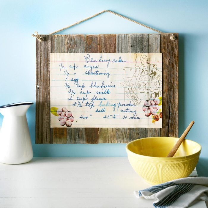 recipe card on wooden sign hanging on a blue wall in kitchen