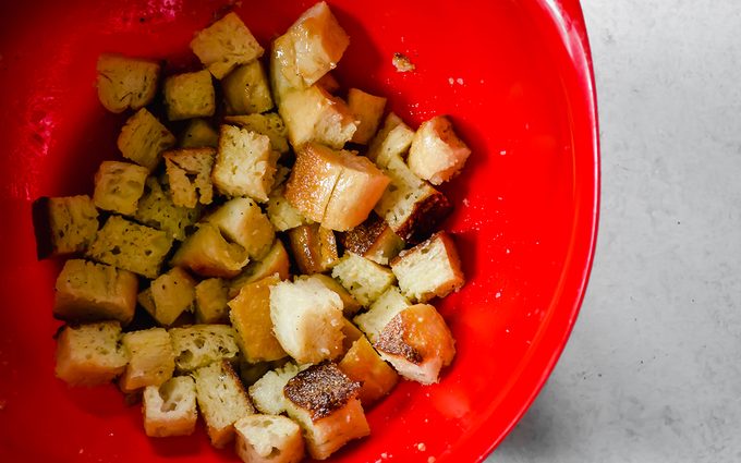 Mixing homemade croutons with seasoning and oil.
