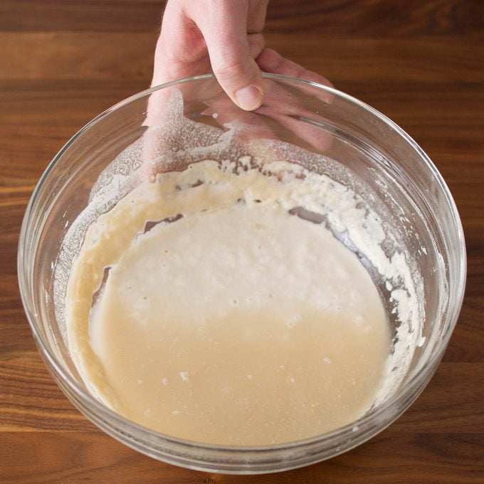 A bowl of sourdough starter with liquid on top.