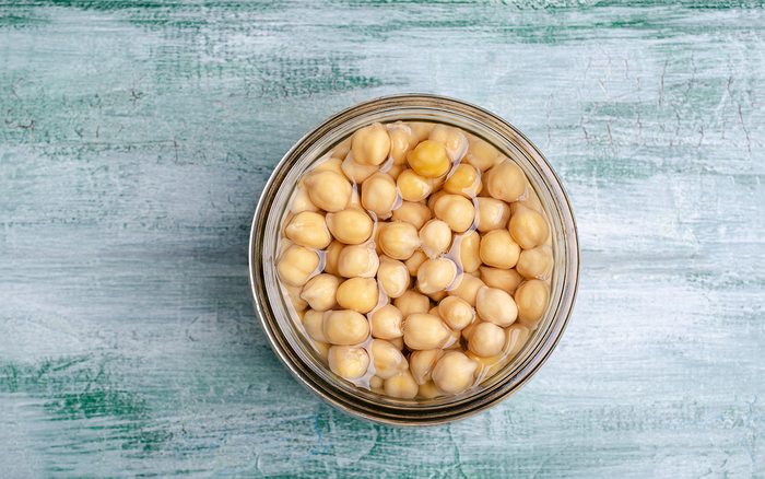 Canned chickpeas in a glass jar on a wooden background. Selective focus.