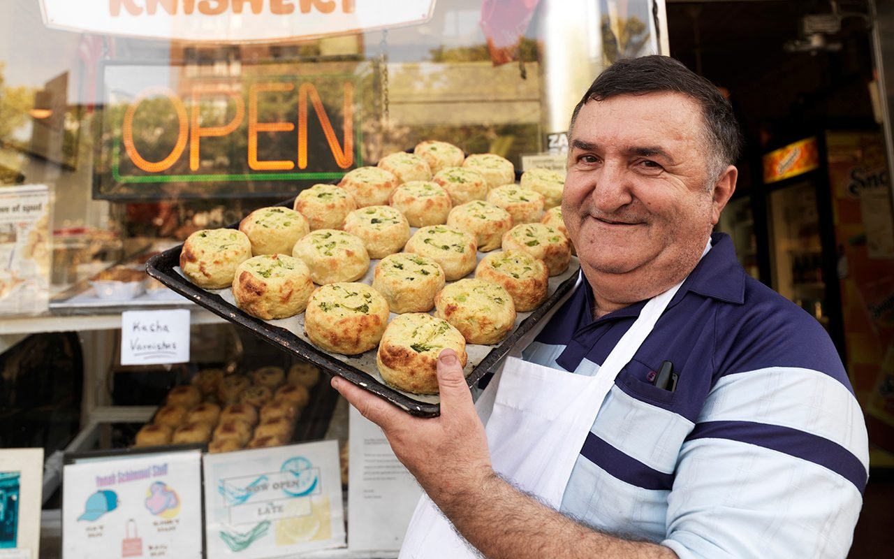 Yonah Schimmel standing outside his Lower East Side Knishery, proudly displaying his famous knishes.