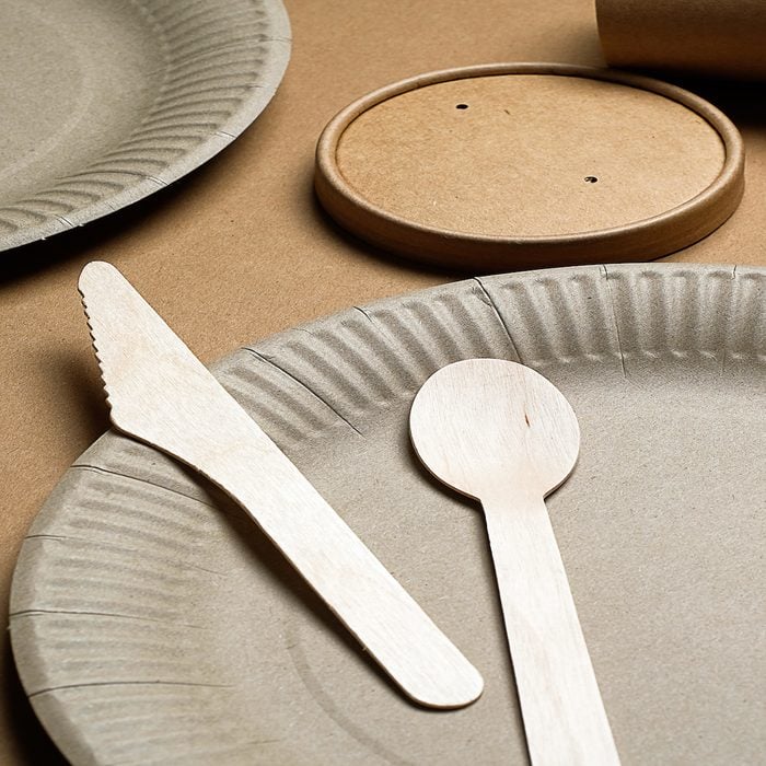 Disposable ECO-friendly tableware made of bamboo wood and paper on a cardboard background. The photo is covered in graininess and noise.