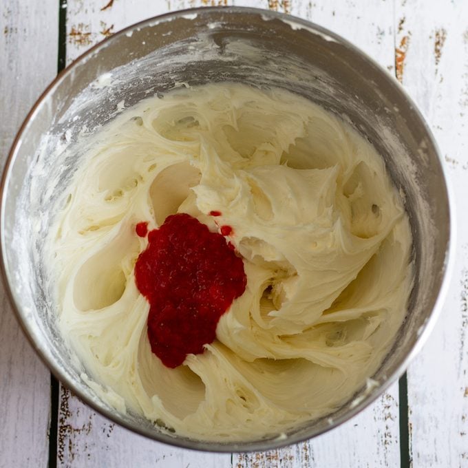 Mixing bowl holding blended butter and cream cheese plus strawberry puree.