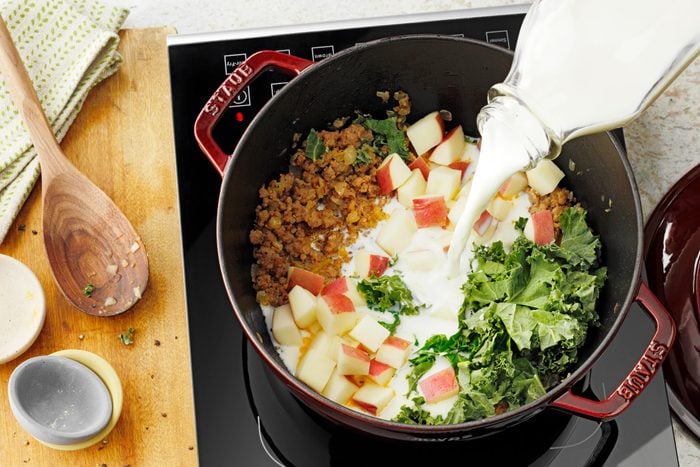 adding milk to other ingredients to a large stock pot for soup