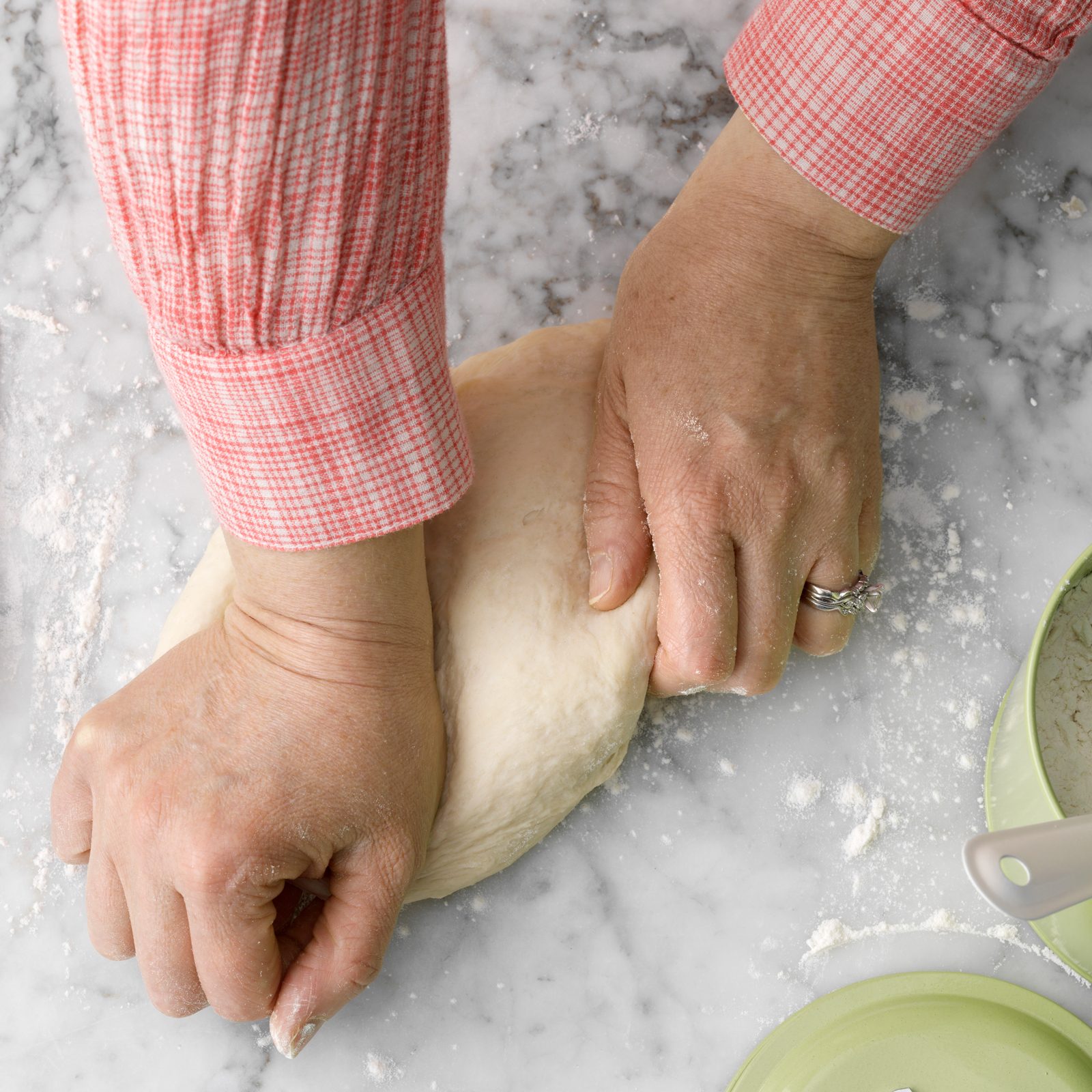 hands stretching pizza dough on a counter