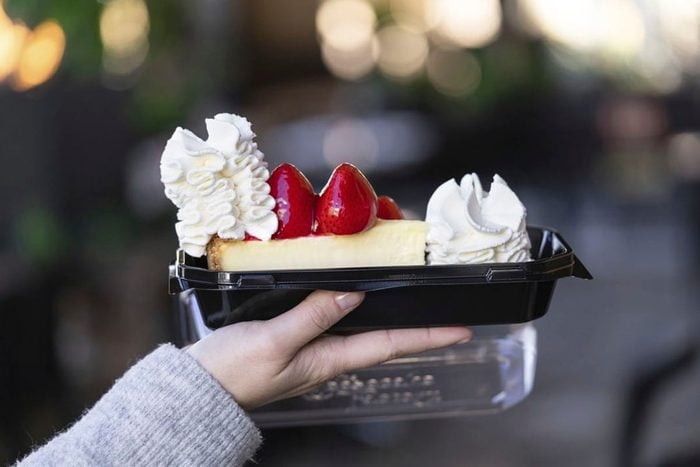 Strawberry Cheesecake from Cheesecake Factory in to go container being held in hand