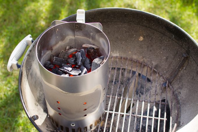 Chimney starter over charcoal grill.