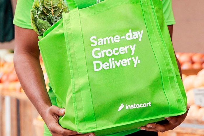 Man carrying groceries in green bag with Instacart advertising bag