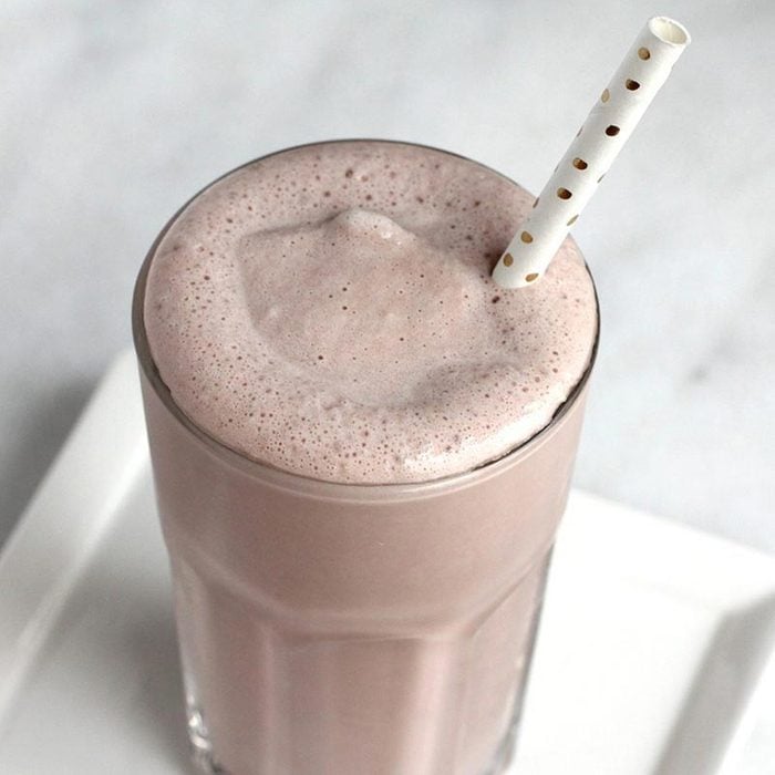 copycat Wendy's chocolate frosty in a clear glass with a dotted paper straw