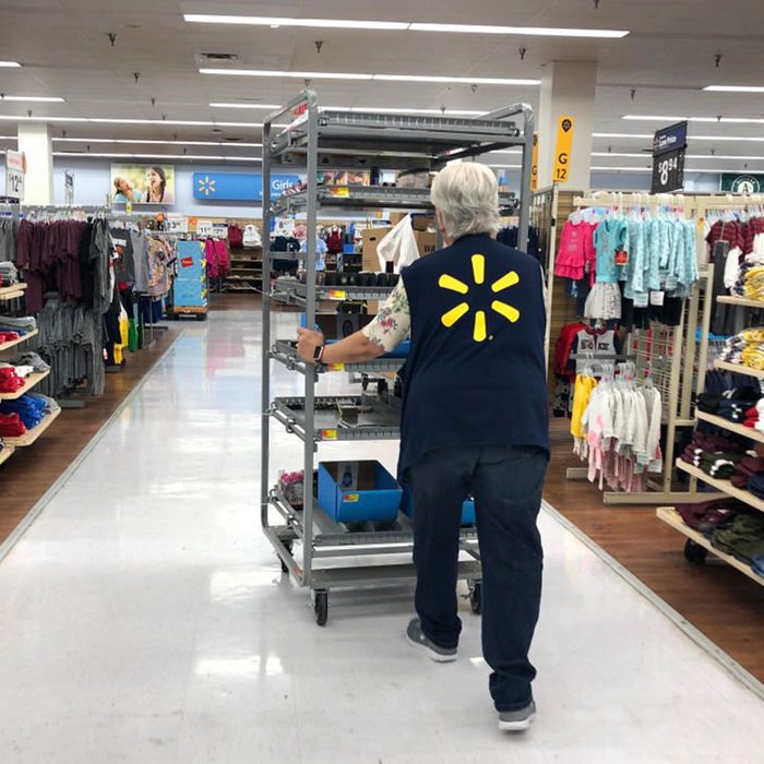Walmart employee pushing a cart full of product down an aisle