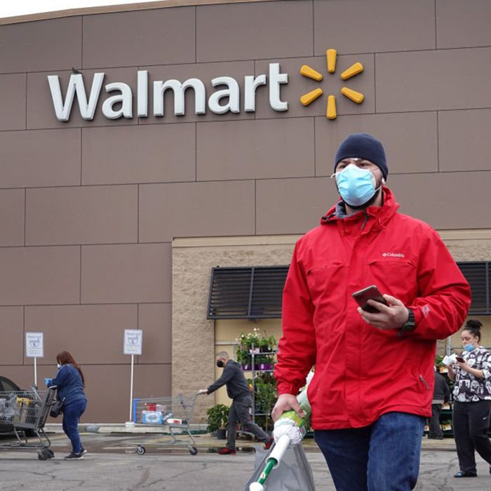 Man wearing a mask walking away from a Walmart