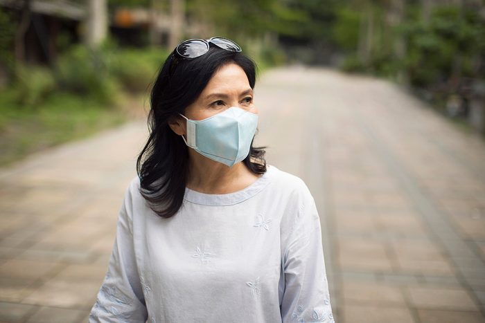 Portrait of a mature Taiwanese woman wearing protective mask over her mouth while walking the streets of Taipei.