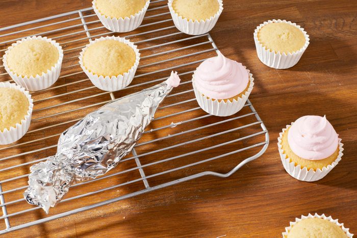 frosting cupcakes with a piping bag made of foil
